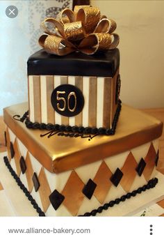 a 50th birthday cake with a gold bow on top and black and white squares around it