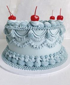 a cake with blue icing and cherries on top