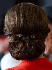 a woman in a red dress is wearing a braided up hairstyle and looking off to the side