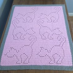 a pink crocheted blanket on a wooden floor