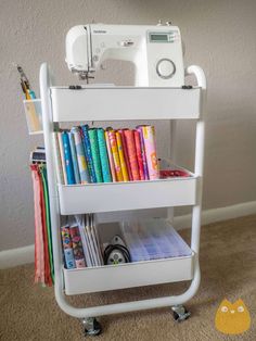 a sewing machine sitting on top of a white shelf filled with books and other items