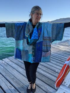 an older woman is standing on a dock with her arms spread out to the side