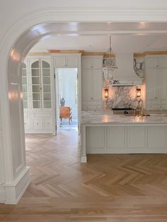 an empty kitchen with white cabinets and wood floors in the middle of a large open floor plan