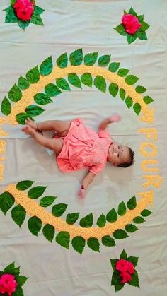 a baby laying on top of a blanket with flowers and leaves painted on it's sides