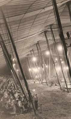 an old black and white photo of people in a tent with lights on the ceiling