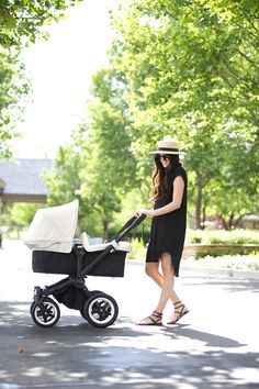 a woman is walking with her baby in a stroller and she has a hat on