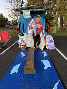 a woman holding a baby standing in the back of a van with decorations on it