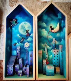 two paintings of buildings with cats flying over them