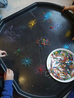 two children at a table playing with magnets and crayons on the tray