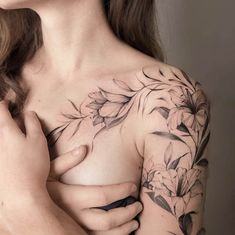 a woman's chest with flowers on it and her hand holding the breast piece