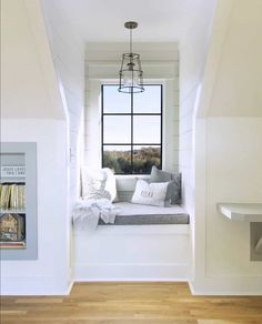 a window seat in the corner of a room with white walls and wood flooring