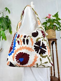 a white bag with flowers on it sitting next to a potted plant