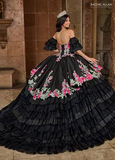 a woman wearing a black dress with pink flowers on it and a tiara around her neck