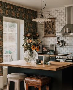 a kitchen island with stools and flowers in a vase sitting on top of it