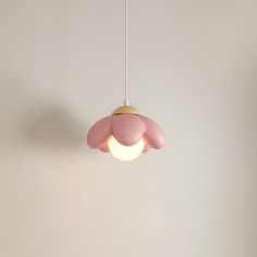 a pink lamp hanging from the ceiling in a room with white walls and flooring