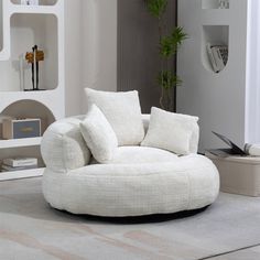 a living room with a white couch and chair next to a book shelf filled with books