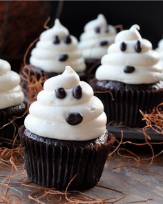 an image of cupcakes with white frosting and chocolate chips on top that look like ghost faces