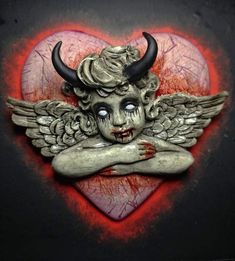 a heart with a statue of a demon on it's face and two horns