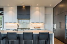 a kitchen with white counter tops and black chairs