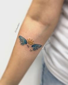 a woman's arm with a small blue bird tattoo on the left side of her arm