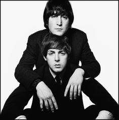 two men sitting next to each other in front of a white background, one with his arms around the other's head