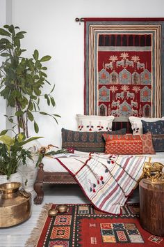 a bed with lots of pillows on top of it next to a potted plant