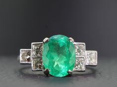 A beautifully  proportioned, bright and vibrant Colombian Emerald is the focal point of this sophisticated and artfully sculpted Gold and Diamond ring. This stunning ring boosts an oval 2.35 carat Colombian Emerald which is flanked by bright white high premium six princess cut sparkling Diamonds, totaling one carat. Quality;  H Colour,  Clarity:  VS1  The Diamonds sparkle and glisten with immense lustre. The Colombian Emerald is set in a secure classic four prong setting and displays a hue of li Gia Certified Oval Emerald Ring In Art Deco Style, Art Deco Oval Emerald Ring With Brilliant Cut, White Gold Oval Emerald Ring Art Deco Style, Luxury Oval Emerald Ring With Diamond Cut, Timeless Oval Diamond Cut Emerald Ring, Modern Oval Brilliant Cut Emerald Ring, Oval Diamond Cut Emerald Ring In Fine Jewelry Style, Oval Emerald Ring With Diamond Cut In Platinum, Modern Gia Certified Oval Rings