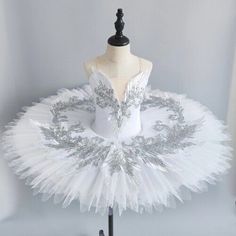 a white ballet tutu with silver sequins on the top and bottom, sitting on a mannequin