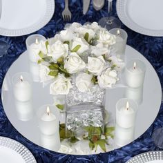 a table set with white roses and candles for an elegant dinner party or special event