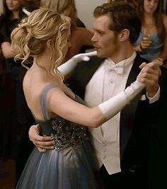 a man in a tuxedo is dancing with a woman wearing a blue dress