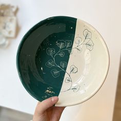 a hand holding a green and white plate