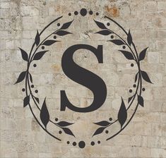 the letter s is surrounded by leaves and berries on a stone wall with a black stencil