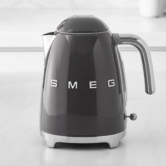 a black and silver smeg kettle sitting on top of a table