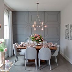 a dining room table is set with white chairs and pink flowers in the vases