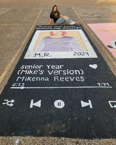 a woman sitting on the side of a road next to a street sign that reads senior year mike's version