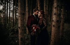 a man and woman are standing in the woods