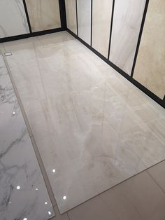 marble flooring in a bathroom with black trim and glass doors on the side wall