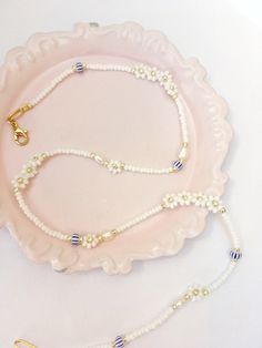 This white and gold beaded pearl and flower necklace is a chic detail to your everyday style. It has a dainty and minimalist look to it and it's perfect for layering. SPECIFICATIONS: Materials: * Tiny real freshwater pearls. * Beaded white flowers with gold centre. * Blue white striped Czech glass beads. * 22 karat goldplated clasp and extender chain. Size: * Lenght: 15-16 inch. Extenderchain inckluded. If you want a different size, please send me a message. I'm happy to make you a custum sized Minimalist White Pearl Chain Beaded Necklace, Dainty White Pearl Chain Jewelry, White Beaded Chain Dainty Jewelry, White Beaded Necklace With Pearl Charm For Summer, White Dainty Beaded Chain Jewelry, Dainty Flower Charm Necklace For Summer, Feminine White Jewelry With Pearl Chain, Dainty White Beaded Chain Jewelry, Dainty White Pearl Necklaces