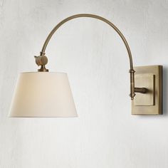 a wall light with a white shade on it's side and a metal arm