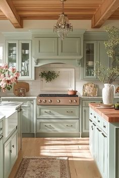 a kitchen filled with lots of green cabinets and counter top space under a chandelier