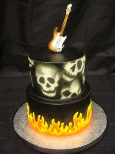 there is a cake with flames and skulls on the top, as well as a guitar