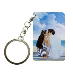 a couple kissing on the beach while holding each other's hand in front of a keychain