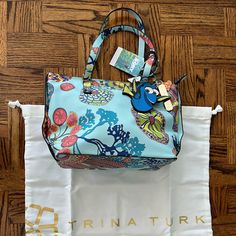 Trina Turk Finding Dory Purse New With Tags With Dust Bag. The Purse Has Two Charms Along With Trina Turk Logo Charm. There Are Two Open Pockets Inside And One Zippered Pocket. It Measures Approximately 12” At The Top By 8” By 5.25”. Chic Blue Floral Print Bag, Blue Floral Print Bag For Vacation, Blue Floral Print Vacation Bag, Blue Floral Print Vacation Bags, Satchel Tote Bag, Satchel Tote, Chain Crossbody Bag, Crossbody Wallet, Tote Bag Purse