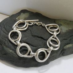 LARGE WRIST - This sterling bracelet measures 7 1/2 inches around the inside when closed. It is 22 mm wide. 59.6 grams sterling silver chain link bracelet, marked 925, vintage, toggle, large wrist. It is an unusual link and lays very nicely. It is marked 925, but I also used acid testing to determine that it is sterling silver. See pictures of the test. It turned a bright red which indicates sterling. Nickel would have turned dark green or black. Guaranteed sterling. PLEASE CHECK THAT IT WILL FIT BEFORE ORDERING.  Thank you.   For more sterling jewelry from MontanaPrairie, follow this link to my Etsy shop.  MontanaPrairie.etsy.com  All my jewelry is pre-owned, vintage or antique and MAY SHOW NORMAL WEAR.  It may (and probably will) need a little polishing to remove tarnish, but if there ar Modern Sterling Silver Bracelets With Toggle Clasp, Modern Sterling Silver Bracelet With Toggle Clasp Gift, Modern Silver Chain Bracelet With Clasp, Unique Sterling Silver Chain Bracelet, Vintage Sterling Silver Bracelets For Everyday, Vintage Sterling Silver Everyday Bracelets, Vintage Sterling Silver Everyday Bracelet, Nickel-free Sterling Silver Chain Link Bracelet, Silver Sterling Chain Bracelet With Hooks And Links