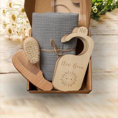 a wooden comb, brush and soap in a gift box with some flowers behind it