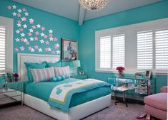 a bedroom with blue walls and white bedding, pink chair, and chandelier