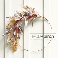 a circular wreath with dried flowers and leaves hanging on a white wooden wall, next to the word mod + birch handmade creations