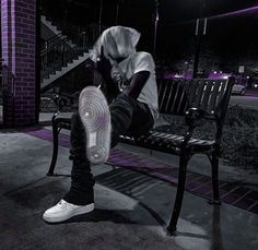 a person sitting on a bench with their feet up in the air while wearing white sneakers