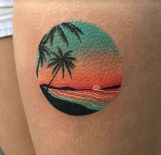 a woman's thigh with a sunset and two palm trees on it, in the shape of a circle