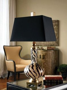 a zebra print lamp sitting on top of a table next to a chair and ottoman